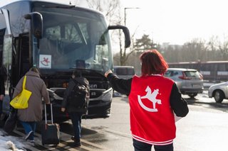 Messebesucher steigen in den Spielwarenmesse-Bus ein, betreut durch Personal mit Spielwarenmesse-Weste