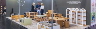 Messestand mit Holz-Kindermöbeln, Regalen und Küchenspielzeug, drei Personen im Gespräch.