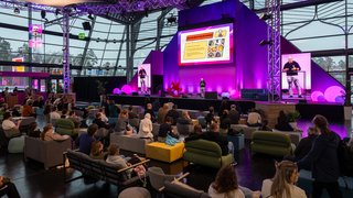 Blick auf die Bühne mit Vortrag und Publikum im Messeforum.