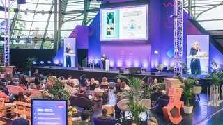 Publikum verfolgt Vortrag auf großer Bühne mit Präsentation beim Toy Business Forum.