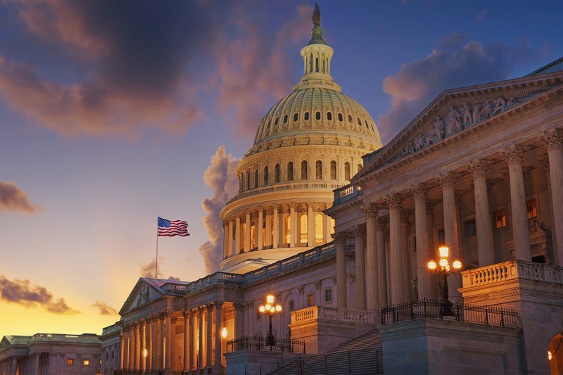 US Capitol at sunset with the American flag waving