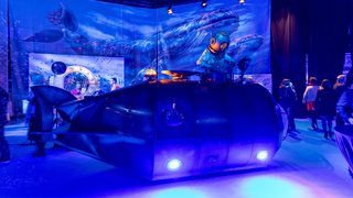 U-Boot-Kulisse mit Taucherfigur, blauer Wal im Hintergrund, Besucher im Ausstellungsraum.