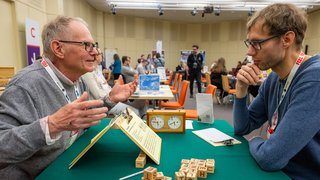 Zwei Personen im Gespräch zu einem Brettspiel.